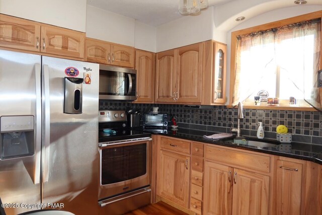 kitchen with tasteful backsplash, sink, dark stone counters, and appliances with stainless steel finishes