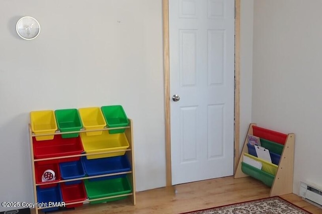 game room with a baseboard radiator and wood finished floors