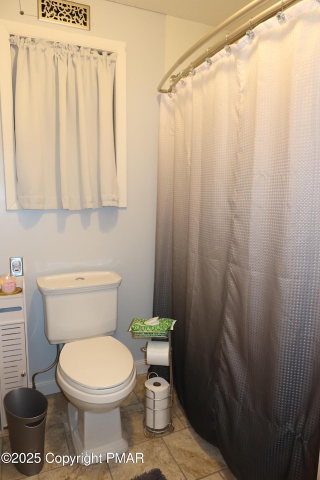 bathroom featuring toilet, curtained shower, and visible vents