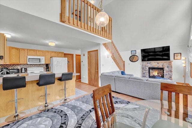 318 N Arrow Dr, Pocono Lake, PA 18347 - dining room with a stone fireplace, stairway, light wood-style flooring, and a high ceiling