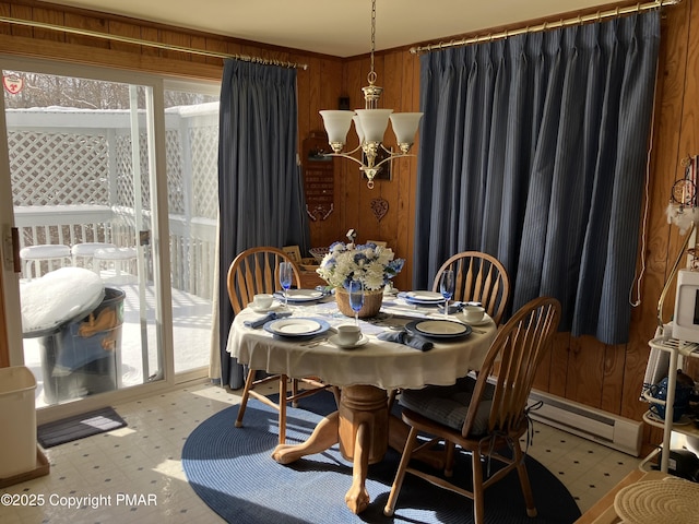 dining room featuring plenty of natural light, light floors, an inviting chandelier, and wood walls