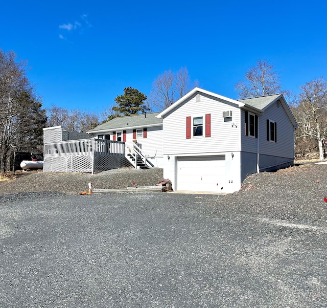 view of front facade featuring a garage, gravel driveway, and a deck