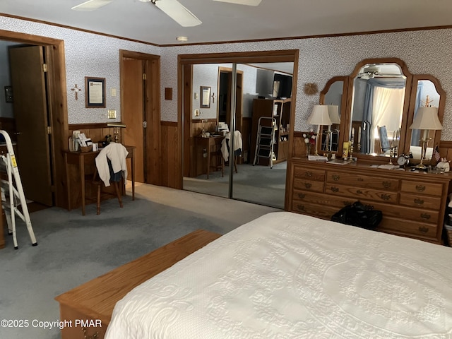 bedroom with wallpapered walls, ornamental molding, a closet, wainscoting, and carpet flooring