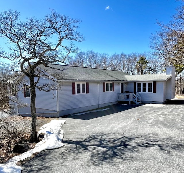 ranch-style home with aphalt driveway and a chimney