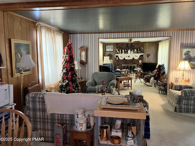 carpeted living area featuring a wealth of natural light, wooden walls, and a fireplace