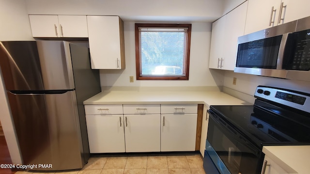 kitchen featuring stainless steel appliances, light countertops, white cabinetry, and light tile patterned floors