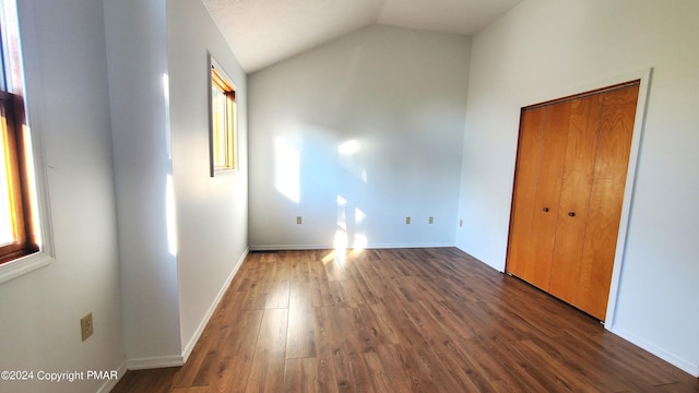 unfurnished bedroom with lofted ceiling, multiple windows, and wood finished floors