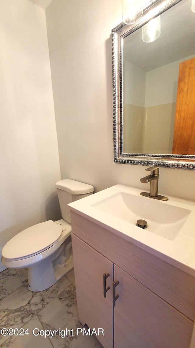 bathroom with toilet, marble finish floor, and vanity