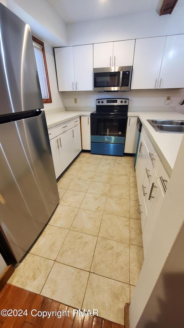 kitchen featuring light countertops, appliances with stainless steel finishes, a sink, and white cabinetry