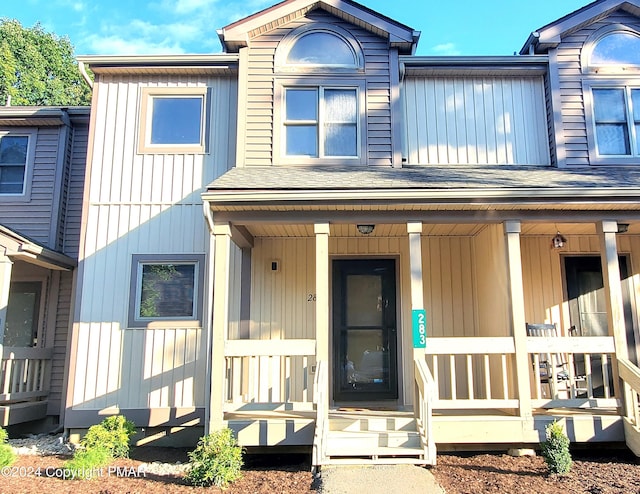 multi unit property with a porch and a shingled roof