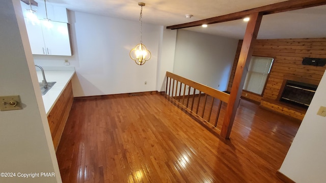 interior space with vaulted ceiling with beams, a sink, baseboards, hardwood / wood-style floors, and a glass covered fireplace