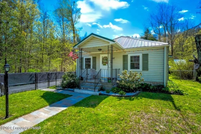 bungalow-style house featuring a front yard, a gate, fence, a porch, and metal roof