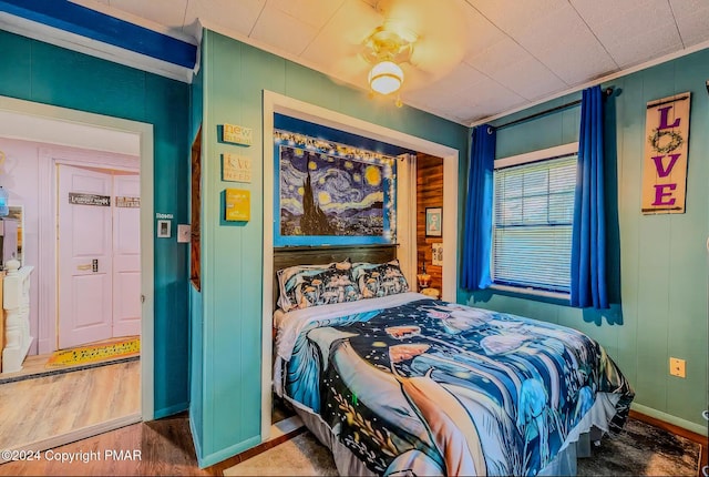bedroom with crown molding, wood finished floors, and baseboards