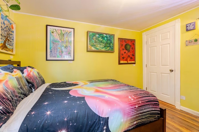 bedroom featuring ornamental molding, baseboards, and wood finished floors