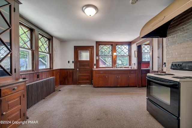 kitchen with range hood, radiator, electric range oven, wainscoting, and light colored carpet