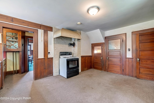 kitchen featuring wooden walls, electric range, wainscoting, custom range hood, and light carpet