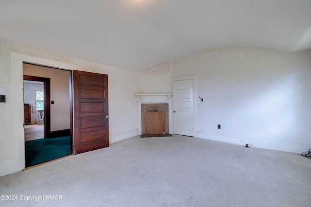 unfurnished living room with carpet floors, a brick fireplace, baseboards, and vaulted ceiling