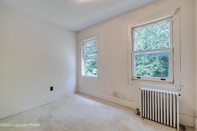 unfurnished room featuring baseboards, radiator heating unit, and carpet