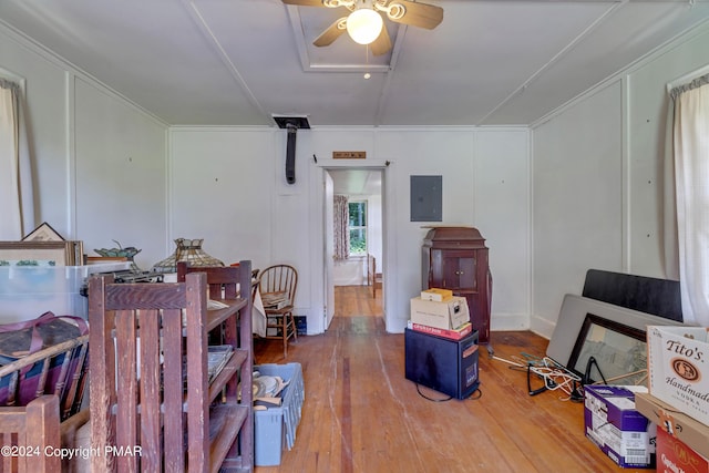 interior space with ornamental molding, electric panel, wood finished floors, a decorative wall, and ceiling fan