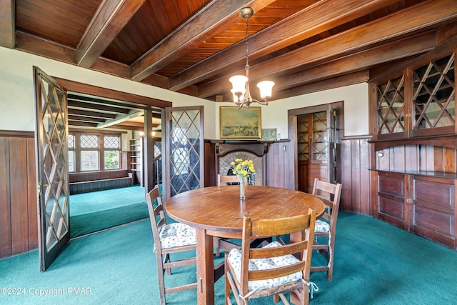 carpeted dining space with a chandelier, a wainscoted wall, wood walls, wood ceiling, and beam ceiling