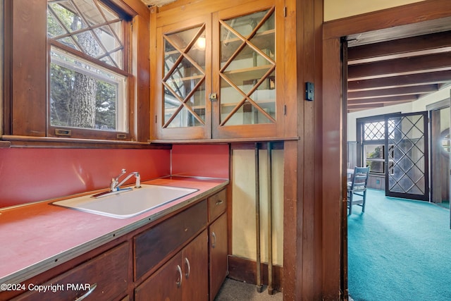 kitchen with beamed ceiling, carpet, and a sink