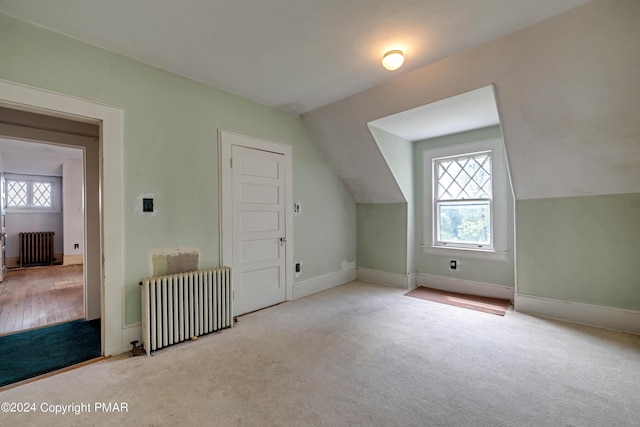 additional living space with carpet flooring, radiator heating unit, and vaulted ceiling