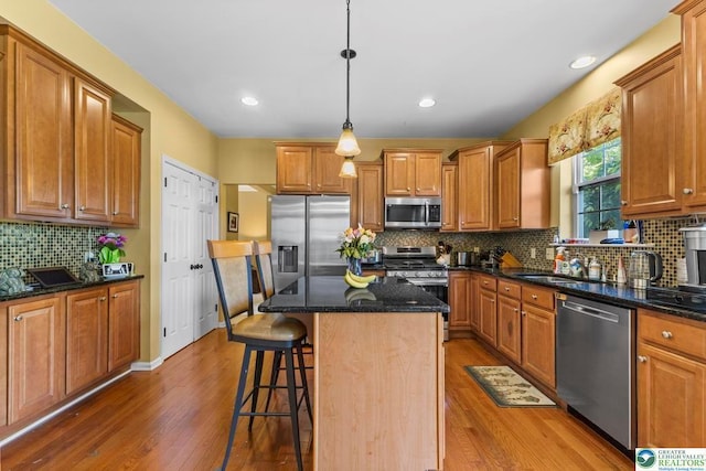 140 Birdie Way, Kunkletown, PA 18058 - kitchen with stainless steel appliances, light wood-style flooring, tasteful backsplash, a kitchen breakfast bar, and dark stone countertops