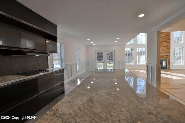 kitchen featuring black electric stovetop, dark cabinets, a decorative wall, open floor plan, and french doors