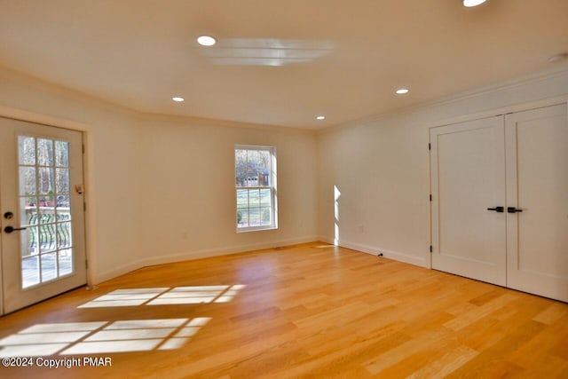 empty room featuring baseboards, light wood-style flooring, and crown molding