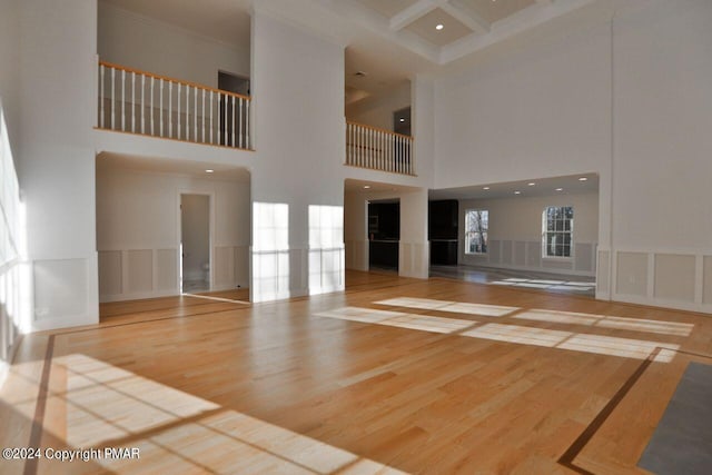 unfurnished living room with ornamental molding, a wainscoted wall, a decorative wall, and wood finished floors