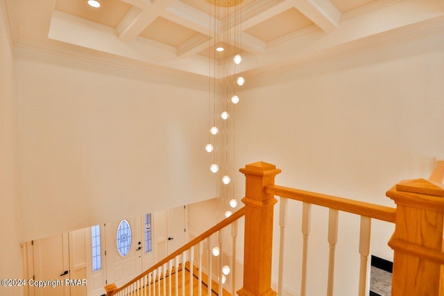 staircase featuring ornamental molding, a high ceiling, coffered ceiling, and beam ceiling