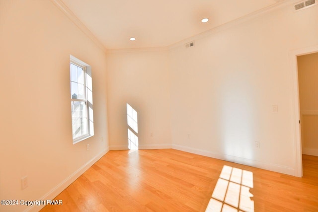 unfurnished room with light wood finished floors, ornamental molding, visible vents, and baseboards