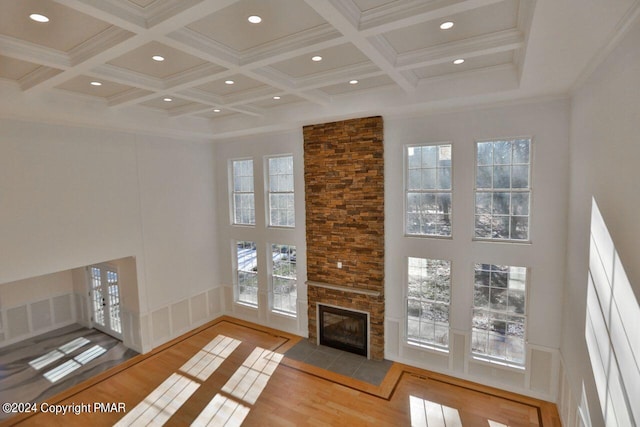 living room featuring a high ceiling, ornamental molding, wood finished floors, coffered ceiling, and beamed ceiling