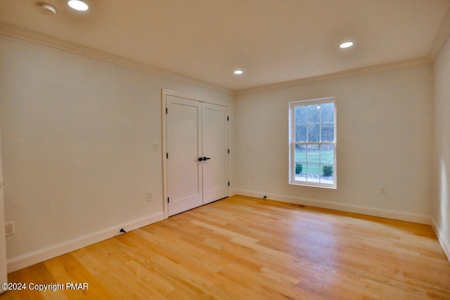 spare room with baseboards, recessed lighting, light wood-type flooring, and crown molding