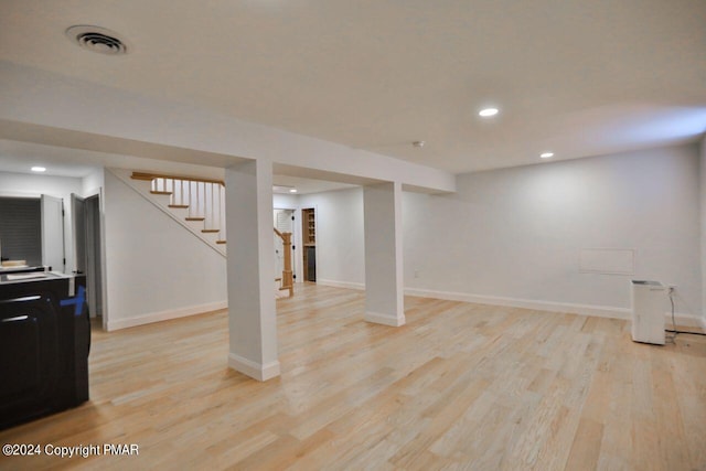 finished basement with stairs, light wood finished floors, visible vents, and baseboards