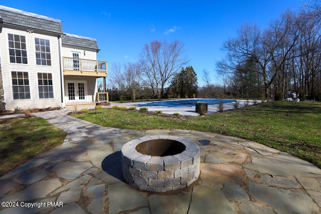 view of swimming pool featuring french doors, a yard, an outdoor fire pit, a patio area, and a covered pool