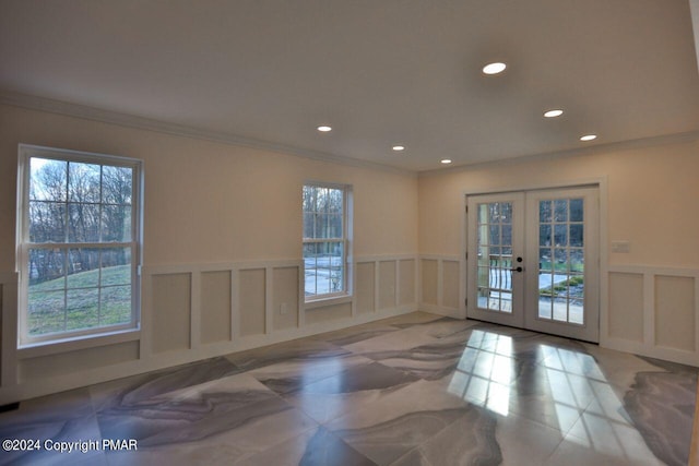 doorway with a healthy amount of sunlight, a decorative wall, crown molding, and french doors