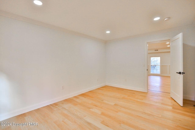 empty room featuring light wood finished floors, ornamental molding, and baseboards