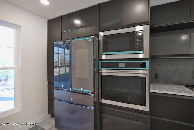 kitchen featuring modern cabinets, appliances with stainless steel finishes, light stone counters, backsplash, and recessed lighting