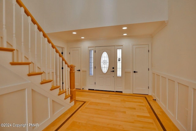 entrance foyer with crown molding, light wood-style floors, recessed lighting, and a decorative wall