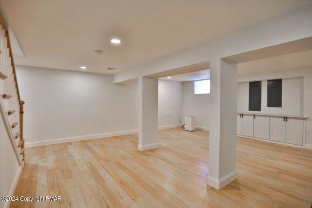 basement with recessed lighting, light wood-style flooring, baseboards, and stairs