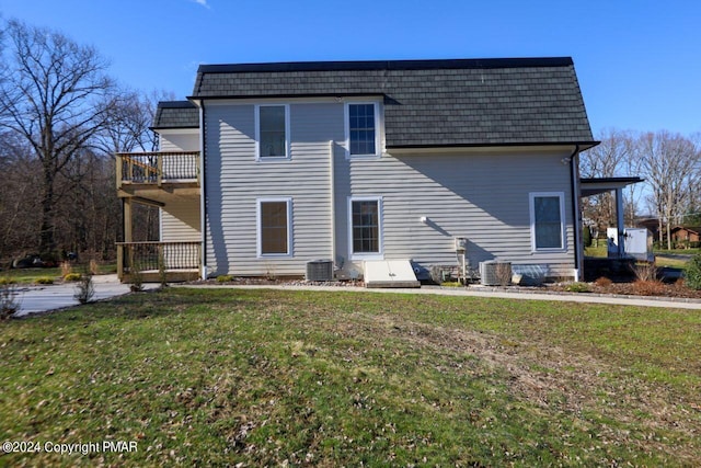 back of property with central AC, a lawn, a balcony, and mansard roof