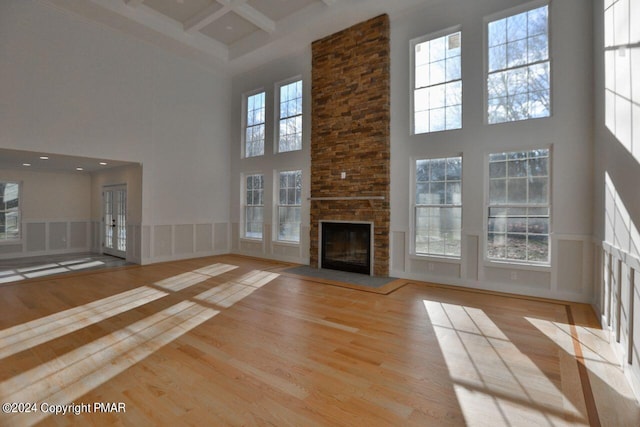 unfurnished living room featuring a high ceiling, coffered ceiling, wood finished floors, and beamed ceiling