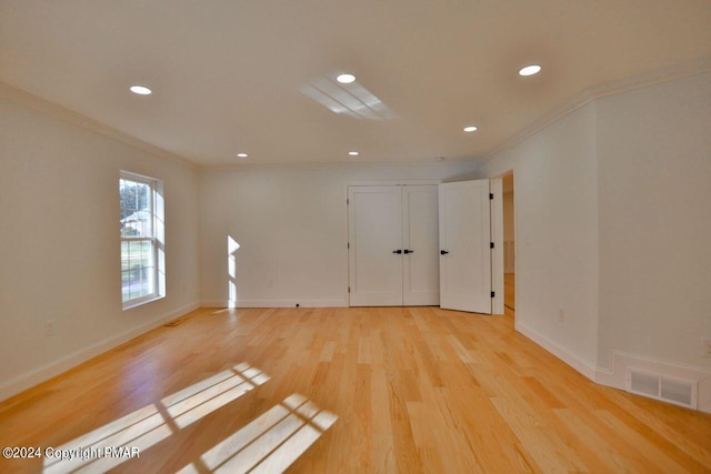 unfurnished room featuring ornamental molding, light wood-style flooring, visible vents, and baseboards