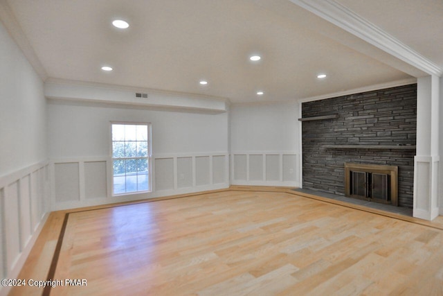 unfurnished living room featuring ornamental molding, visible vents, a fireplace, and wood finished floors