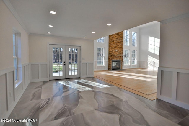 living room with crown molding, french doors, a wainscoted wall, and a decorative wall