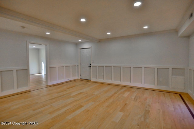 empty room with a wainscoted wall, recessed lighting, a decorative wall, ornamental molding, and wood finished floors