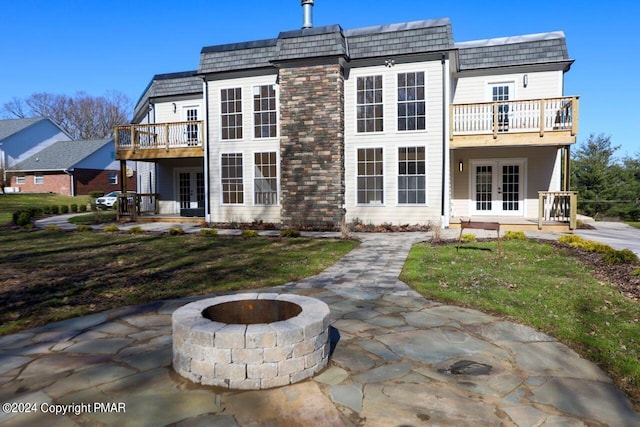 back of house featuring an outdoor fire pit, french doors, a balcony, and mansard roof