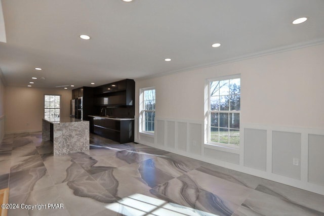 kitchen with a wealth of natural light, marble finish floor, a wainscoted wall, and a decorative wall