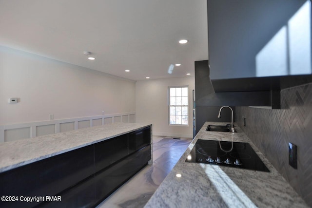 kitchen with light stone countertops, black electric cooktop, a sink, and recessed lighting